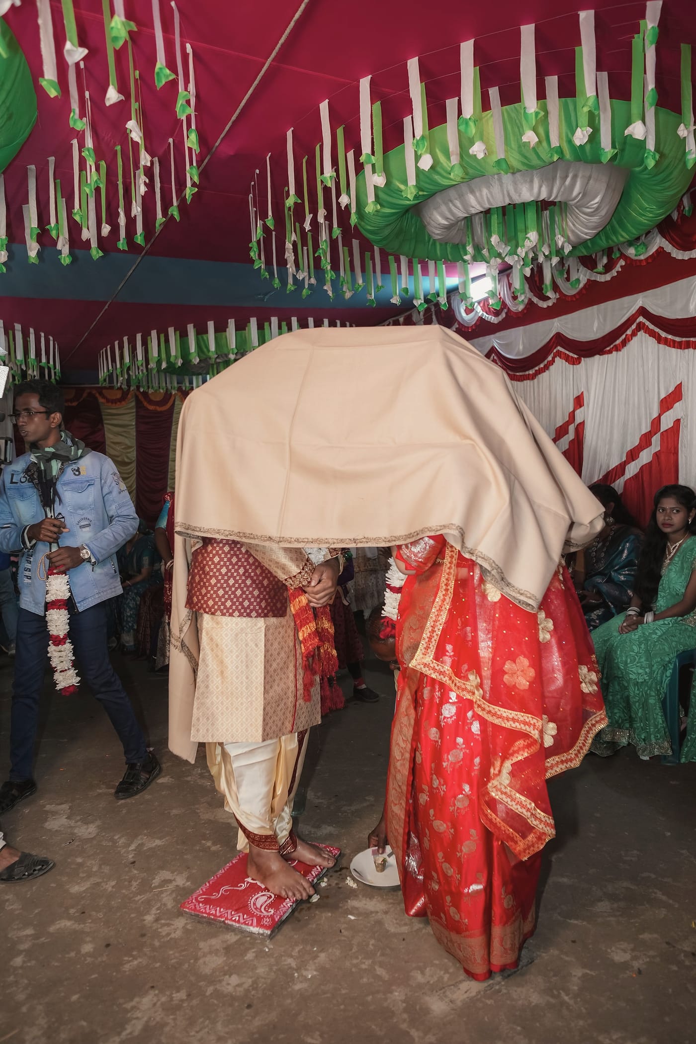 The couple standing close under a cream cloth held above them