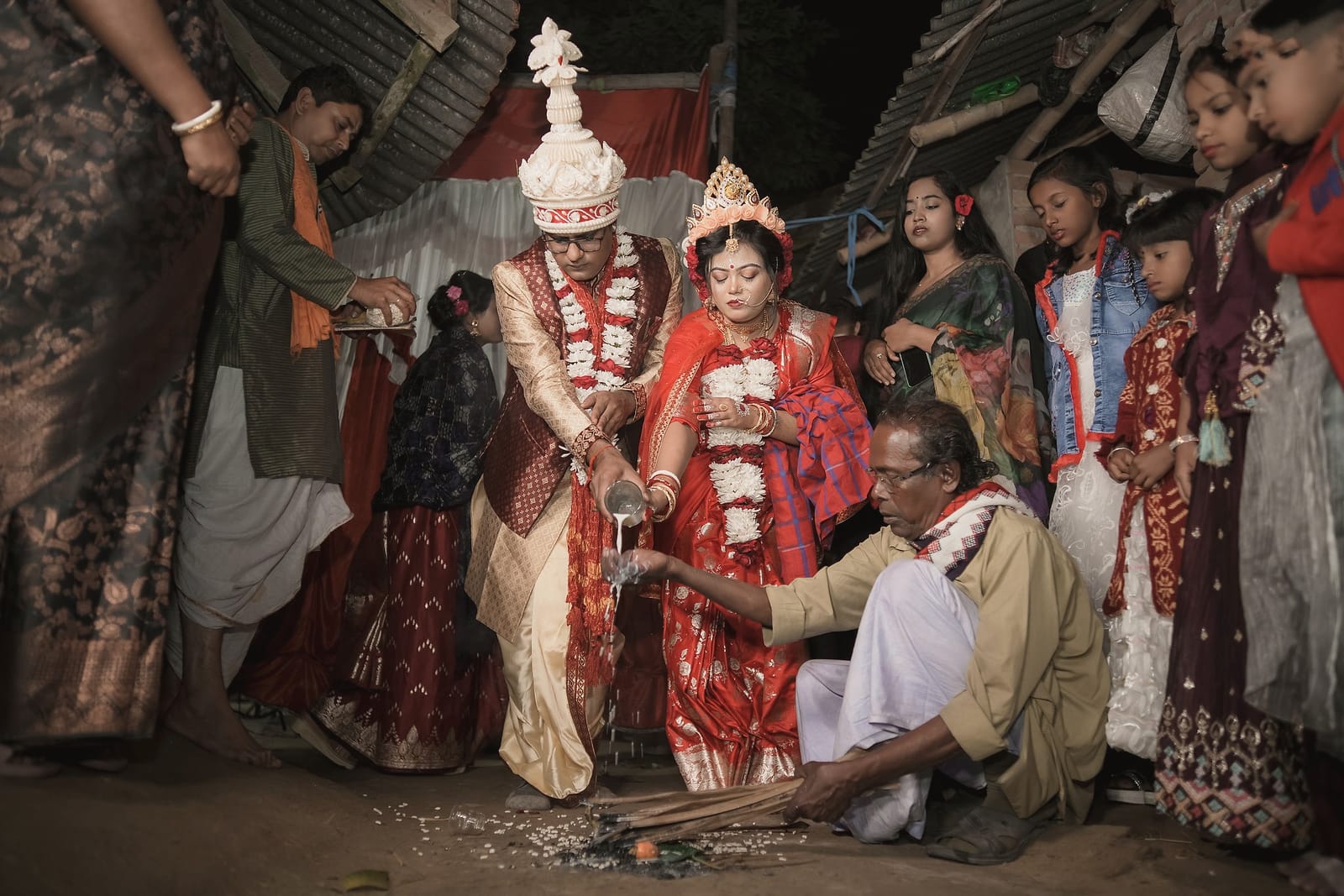 The couple seated in garlands among relatives